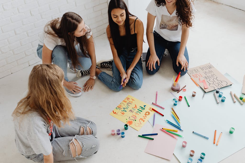 Young women engaged in painting protest signs, fostering creativity and empowerment indoors.